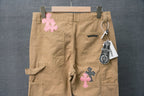 Beige cargo pants with front patch pockets and hanging tag; pink and black check crosses