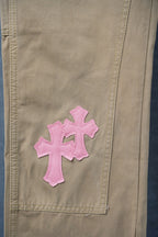 Beige pants with pink cross patch on front pocket area