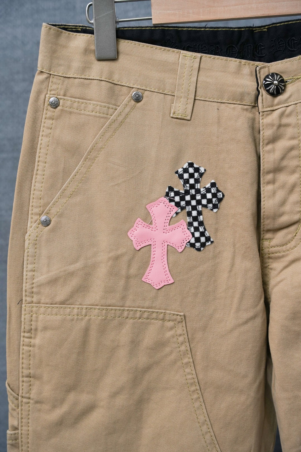 Beige cargo pants with pink and black cross appliques near front pocket