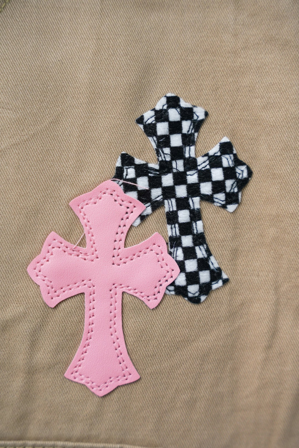 Beige pants close-up: pink cross patch with checkered cross applique