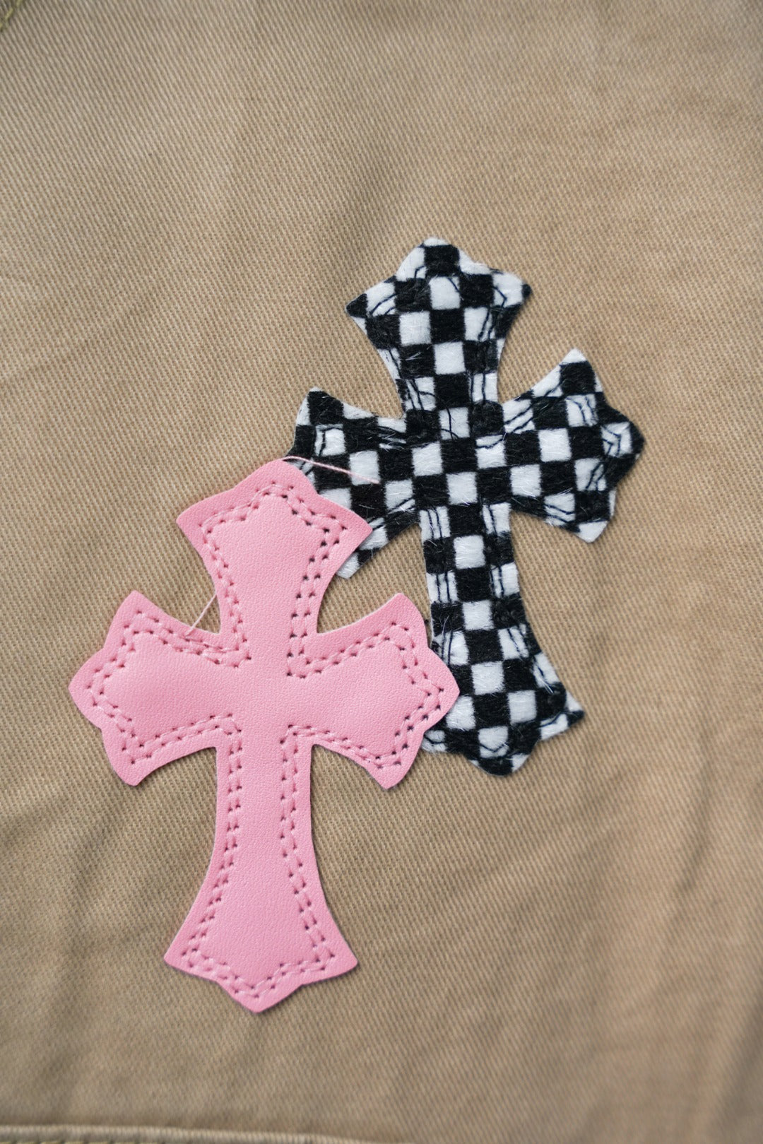 Beige pants close-up: pink cross patch with checkered cross applique
