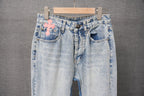 Light blue denim pants with pink cross patch, belt loops, and back pockets