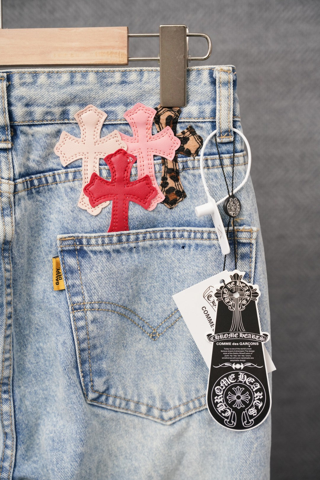 Light blue denim pants with cross patches and hanging logo tag