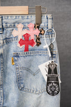 Light-wash denim pants front pocket with colorful cross patches and hanging tags