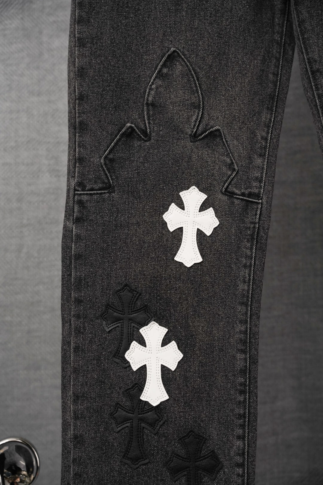 Black denim pant leg with large outline applique and white cross patch