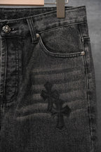 Black denim pants with coin pocket and large dark cross applique, close-up