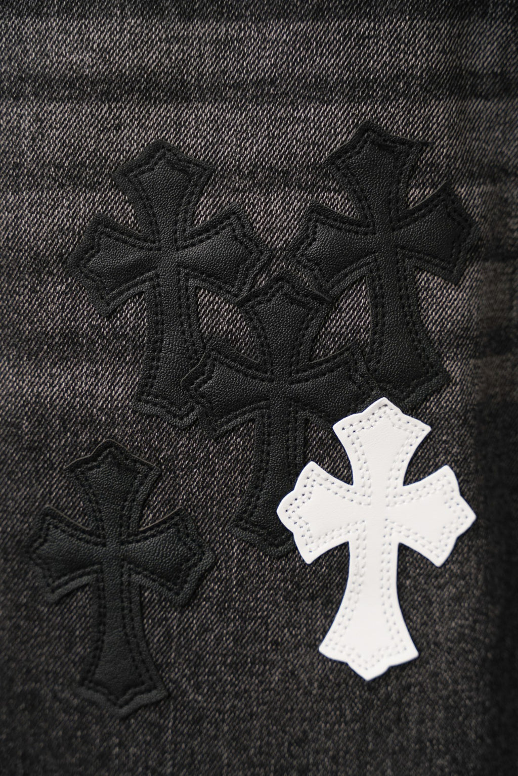 Black denim fabric with embroidered cross patches cluster, one white cross