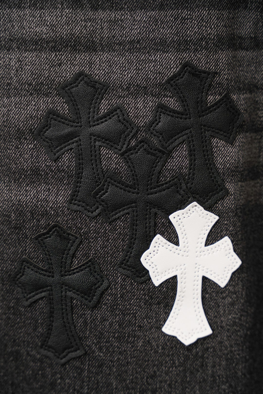 Black denim fabric with embroidered cross patches cluster, one white cross