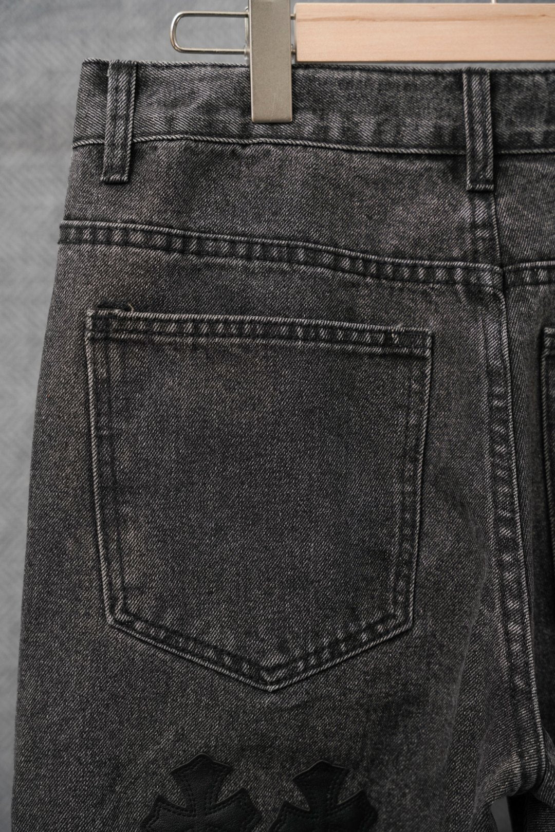 Black denim pants back with stitched pocket panel and belt loops, close-up