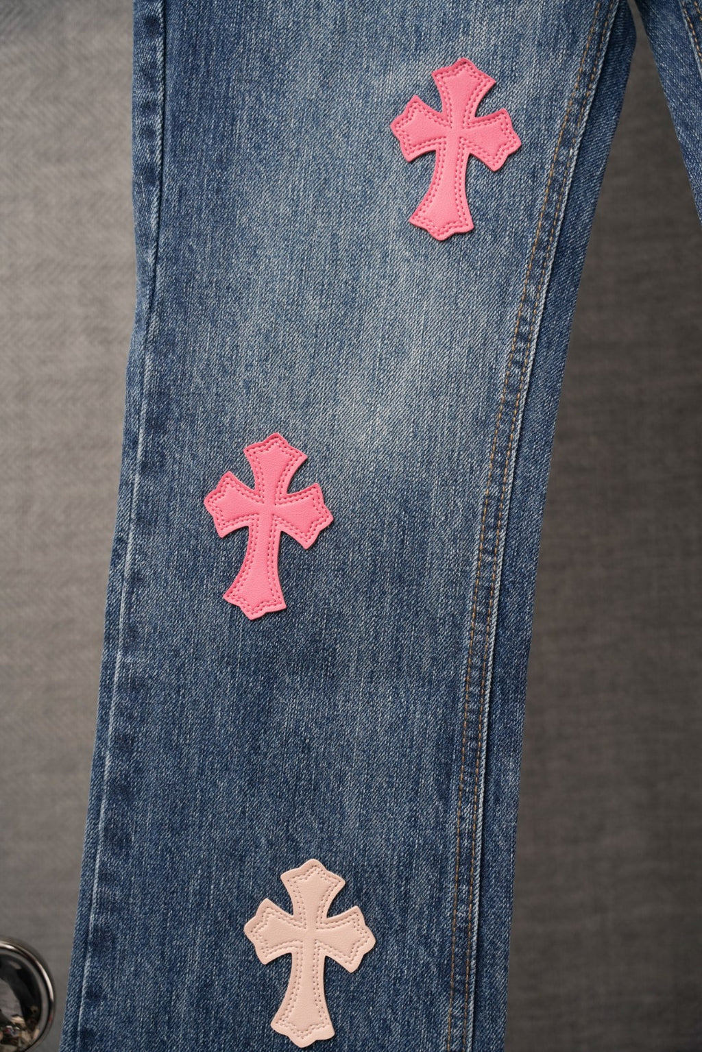 Chrome pants in blue denim with pink and tan cross patches along the side
