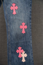 Blue denim Chrome pants with pink cross patches on thigh and leg.