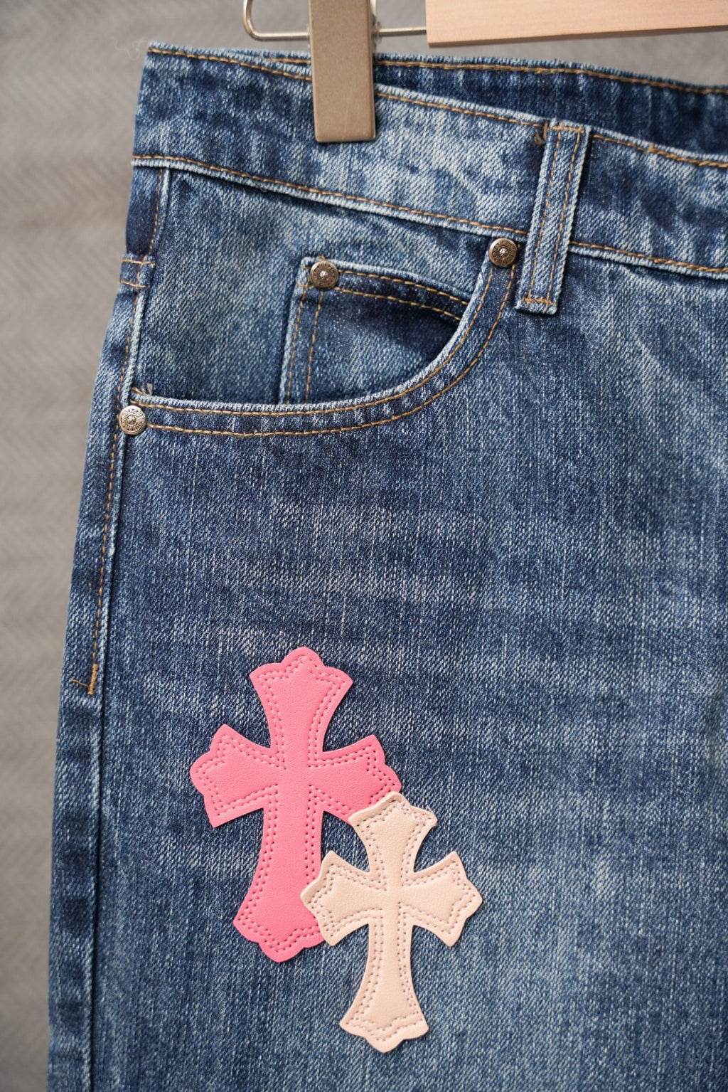 Chrome pants in blue denim with a pink cross patch on the thigh