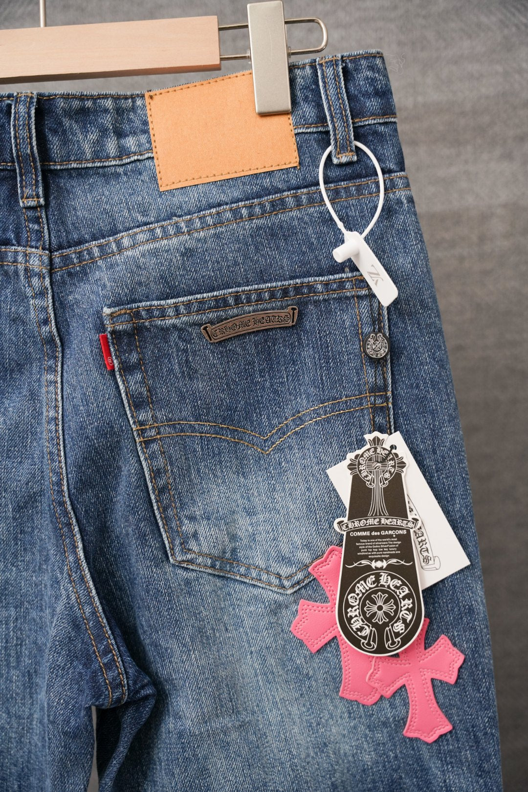 Blue denim jeans front with pocket, belt loop, and hanging charm with cross