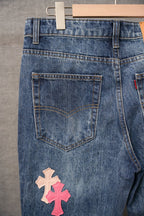 Blue denim pants with back pocket and pink/beige cross patch near the hem