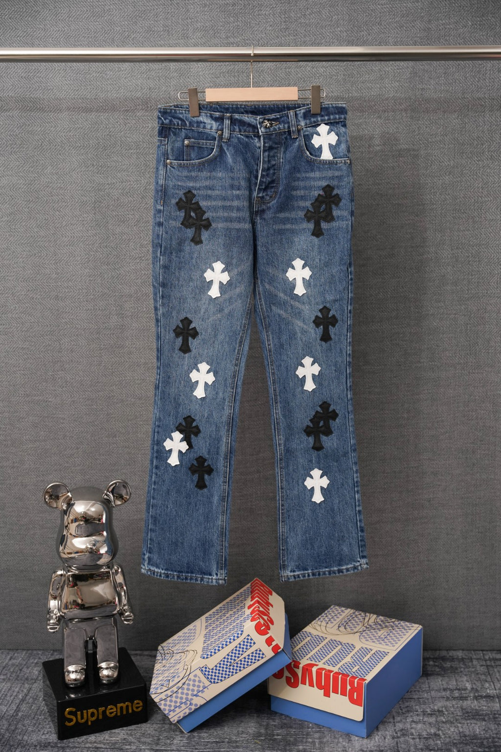 Blue denim pants with dark and white cross patches, straight leg.