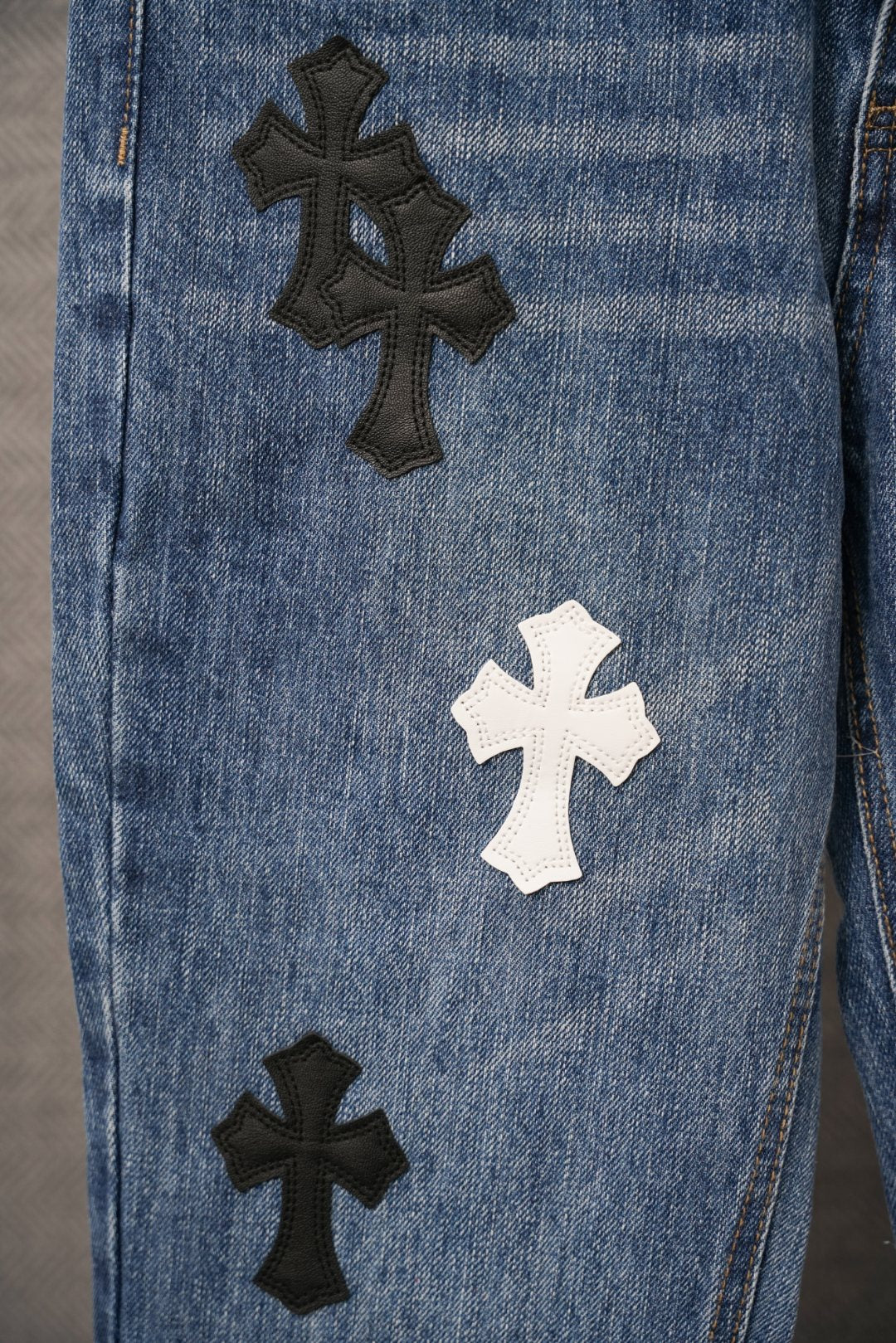 Blue denim pants close-up of thigh with black and white cross patches