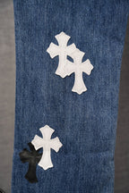 Blue denim pants with white and black cross appliqués on leg