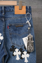 Blue denim pants with white and black cross appliques on front pocket area