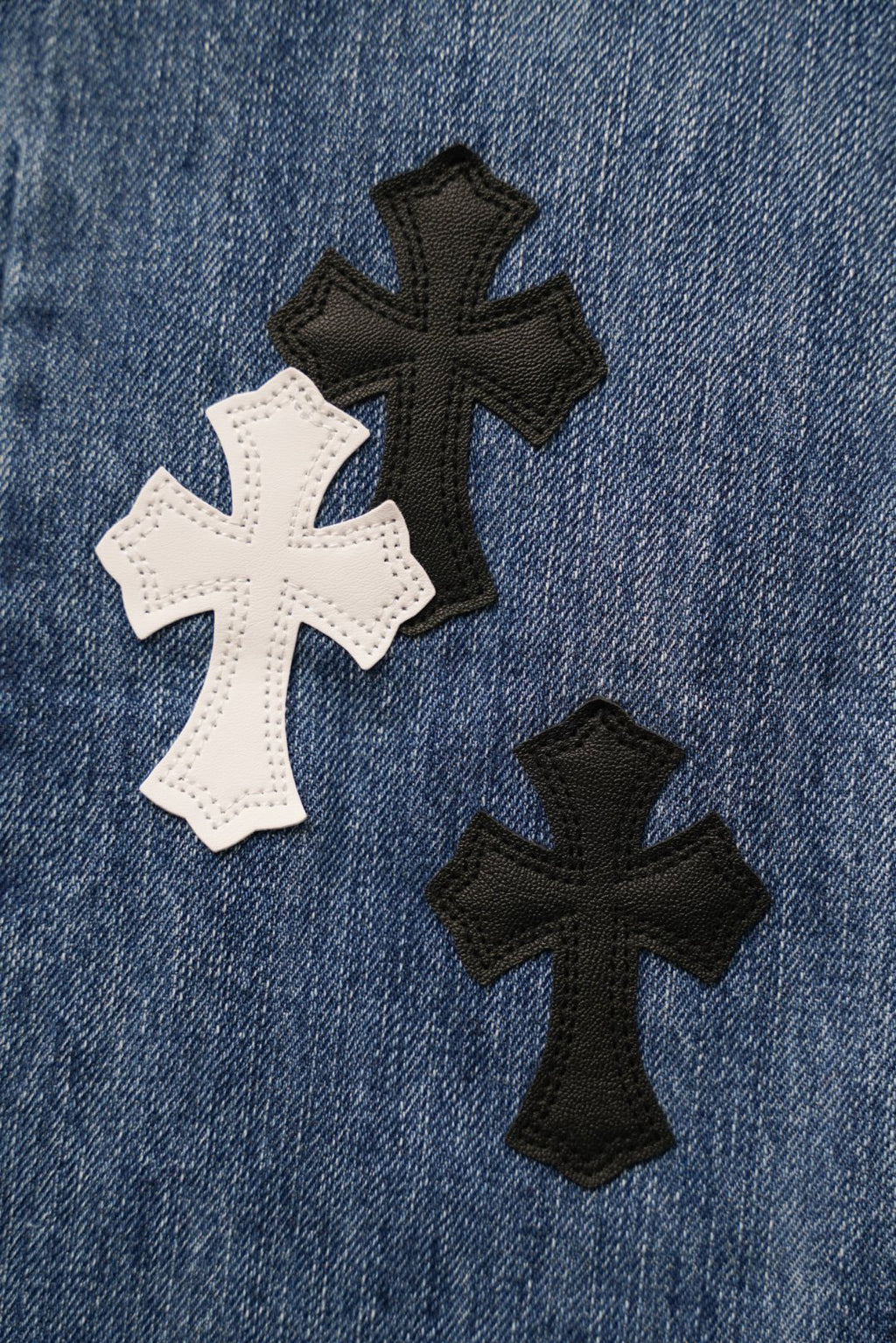 Blue denim pants close-up of cross patches in white and black