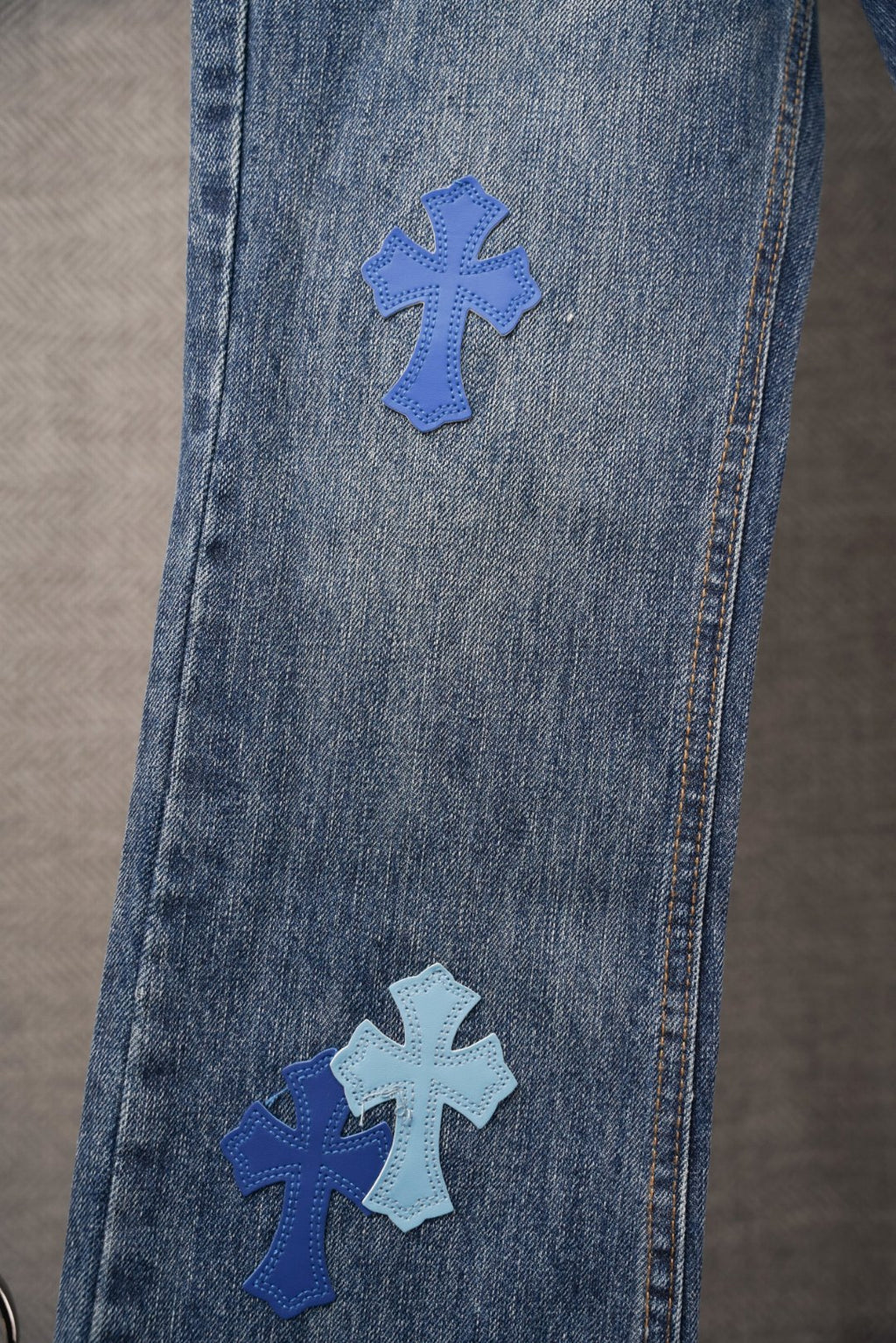 Chrome denim pants with blue cross patches on front leg