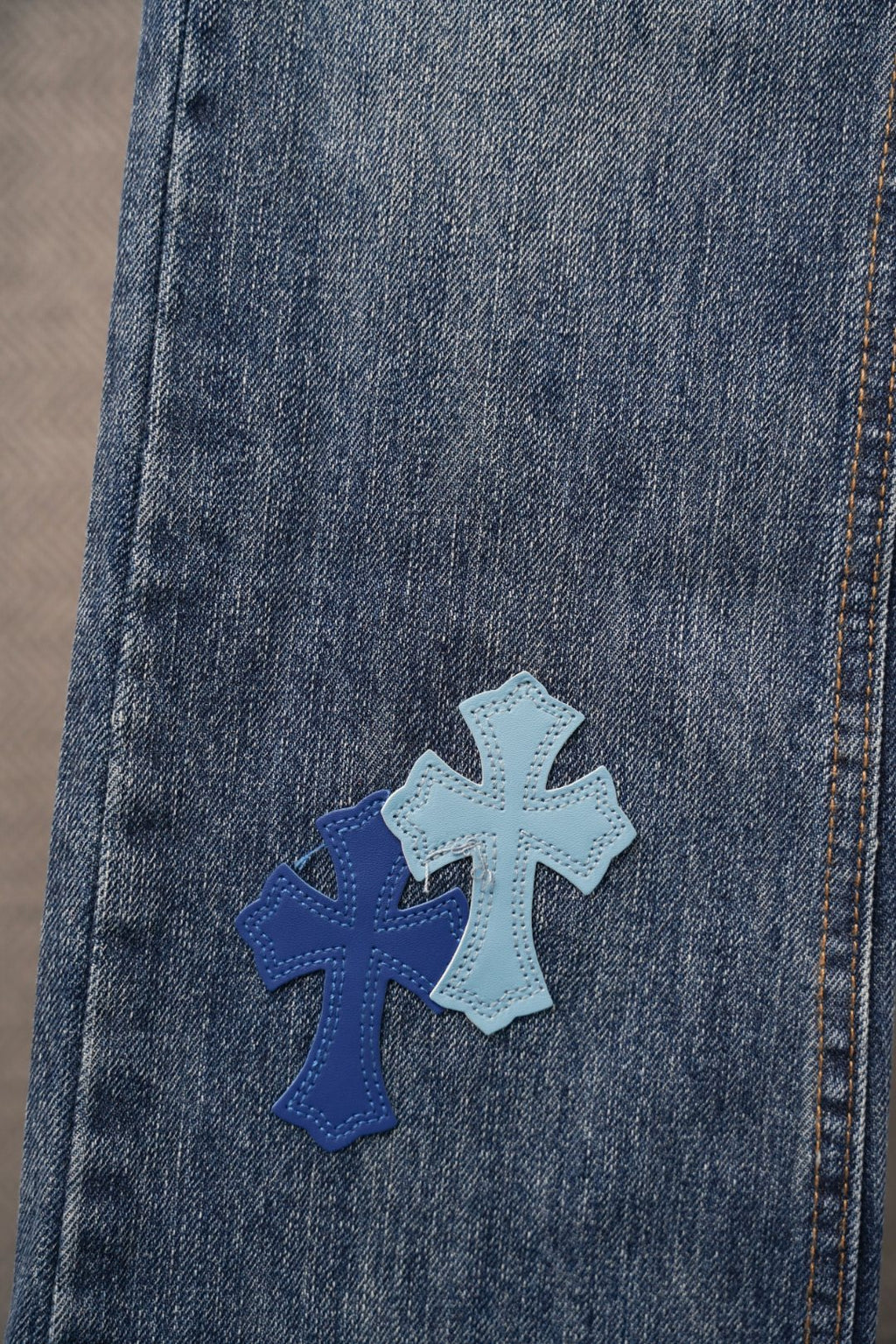 Chrome denim pants with blue cross patch near hem