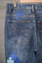 Denim pants close-up: front patch pocket and blue cross emblem on leg