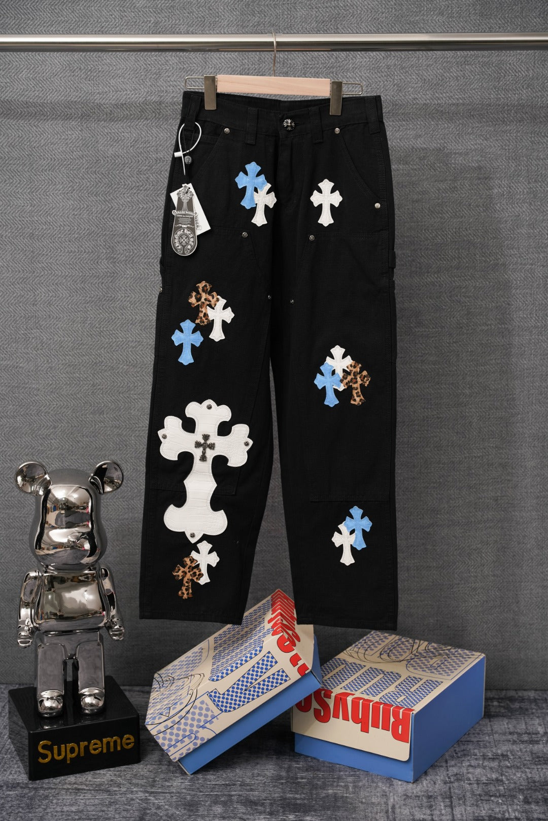 Black pants with blue and white cross applique patches and buttoned front pockets