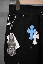 Black pants close-up with blue and white cross patches and hanging tag at belt.