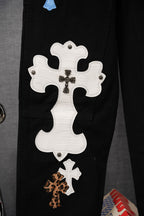 Black pants close-up of large white cross applique with small leopard print cross patch