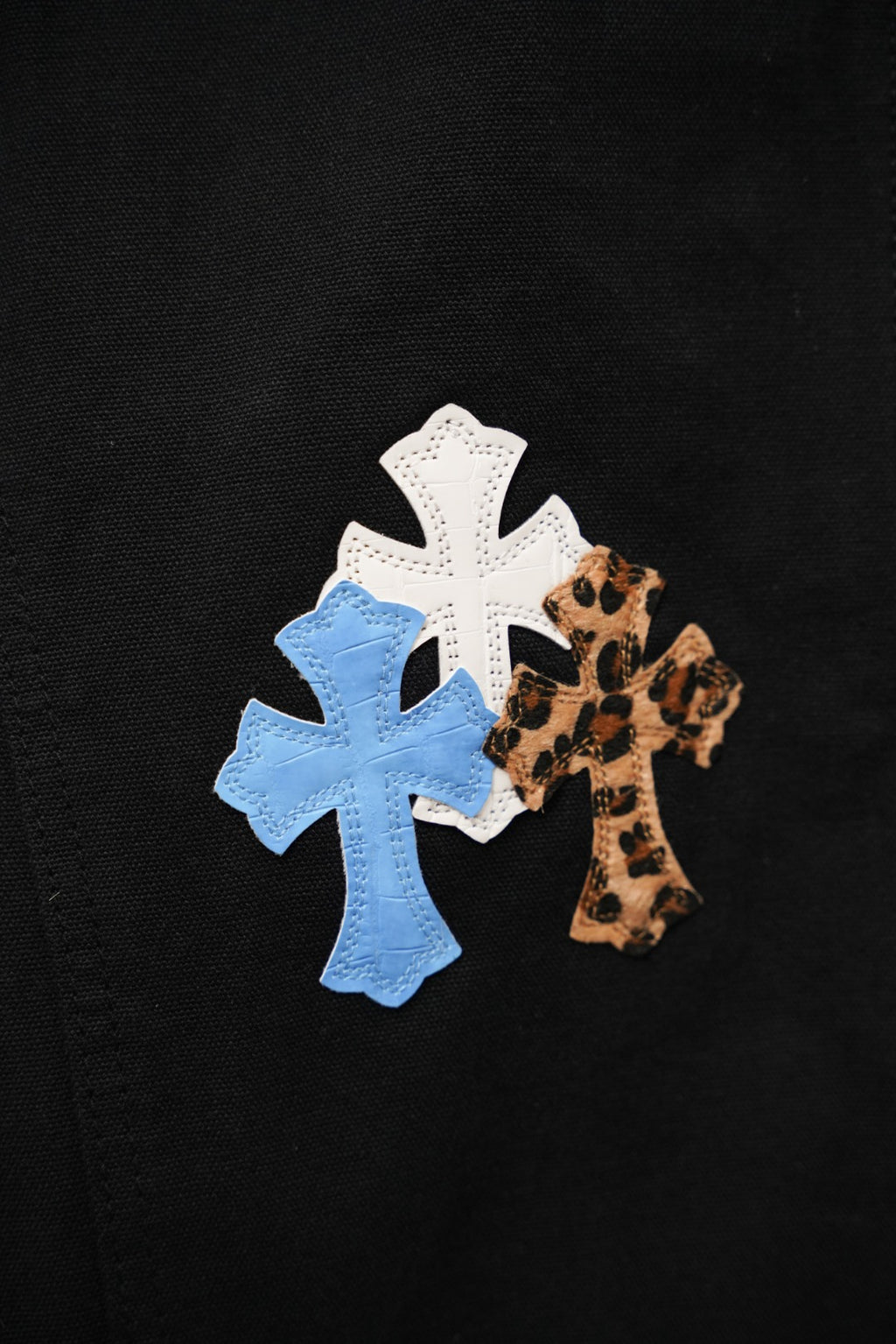 Black pants with white, light blue, and leopard cross appliques