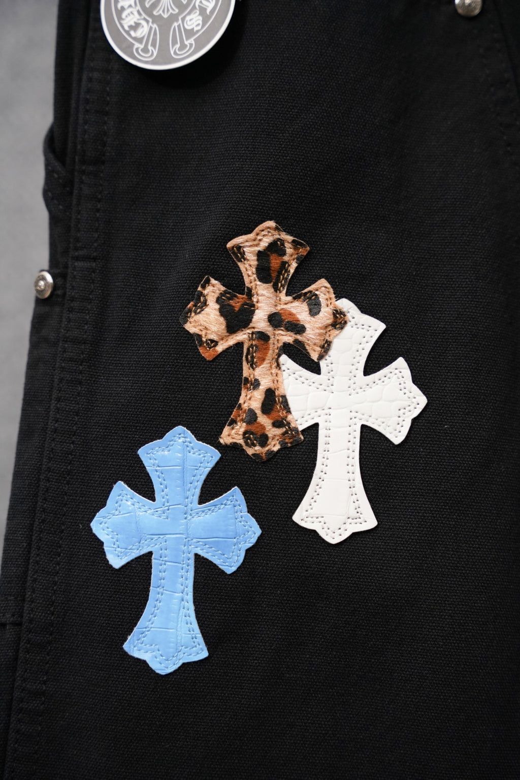 Chrome pants, black denim with leopard and white cross patches with blue cross