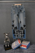 Light-wash denim jeans with black cross and striped appliqué patches