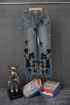 Light-wash denim jeans with black cross and striped appliqué patches