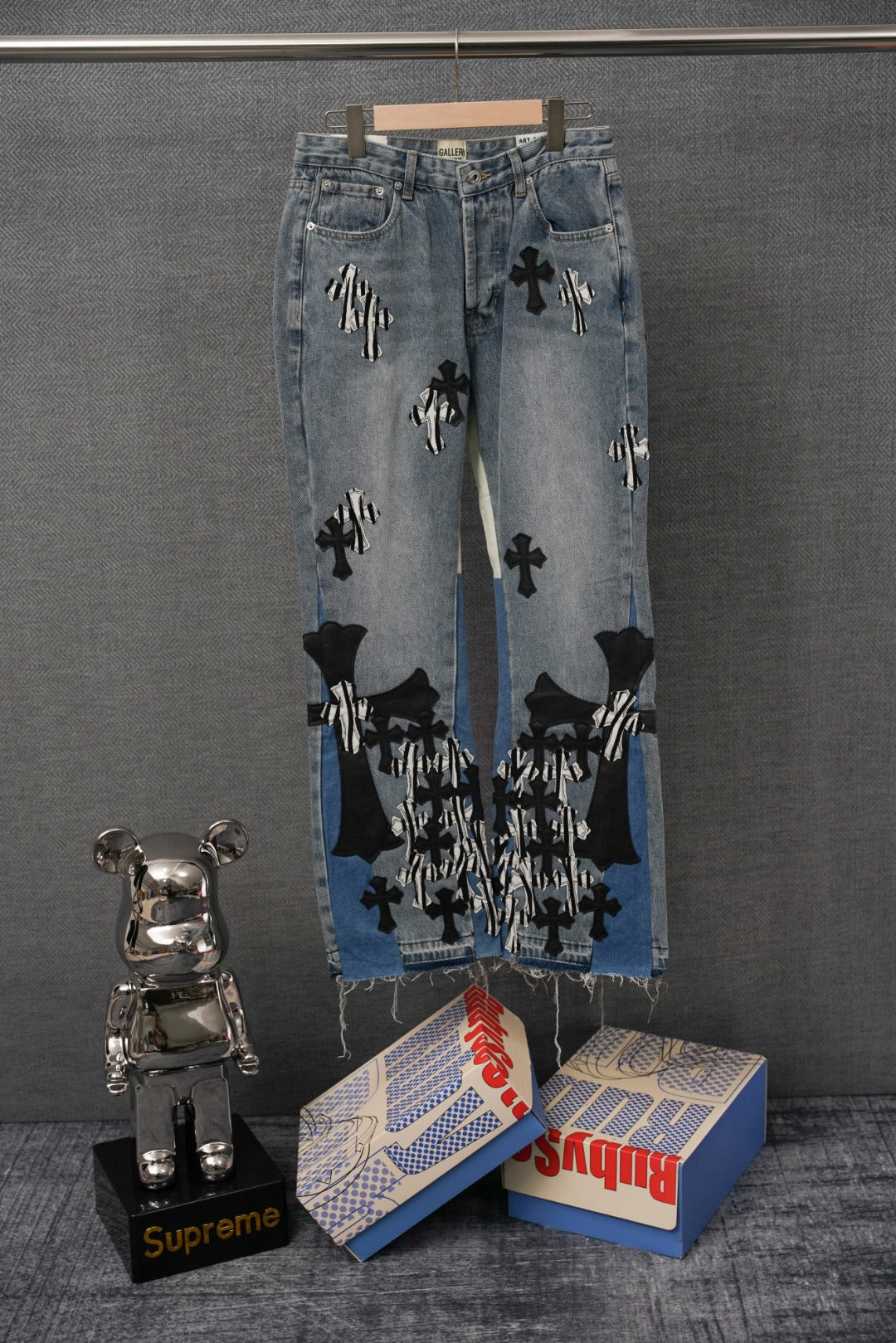 Light-wash denim jeans with black cross and striped appliqué patches