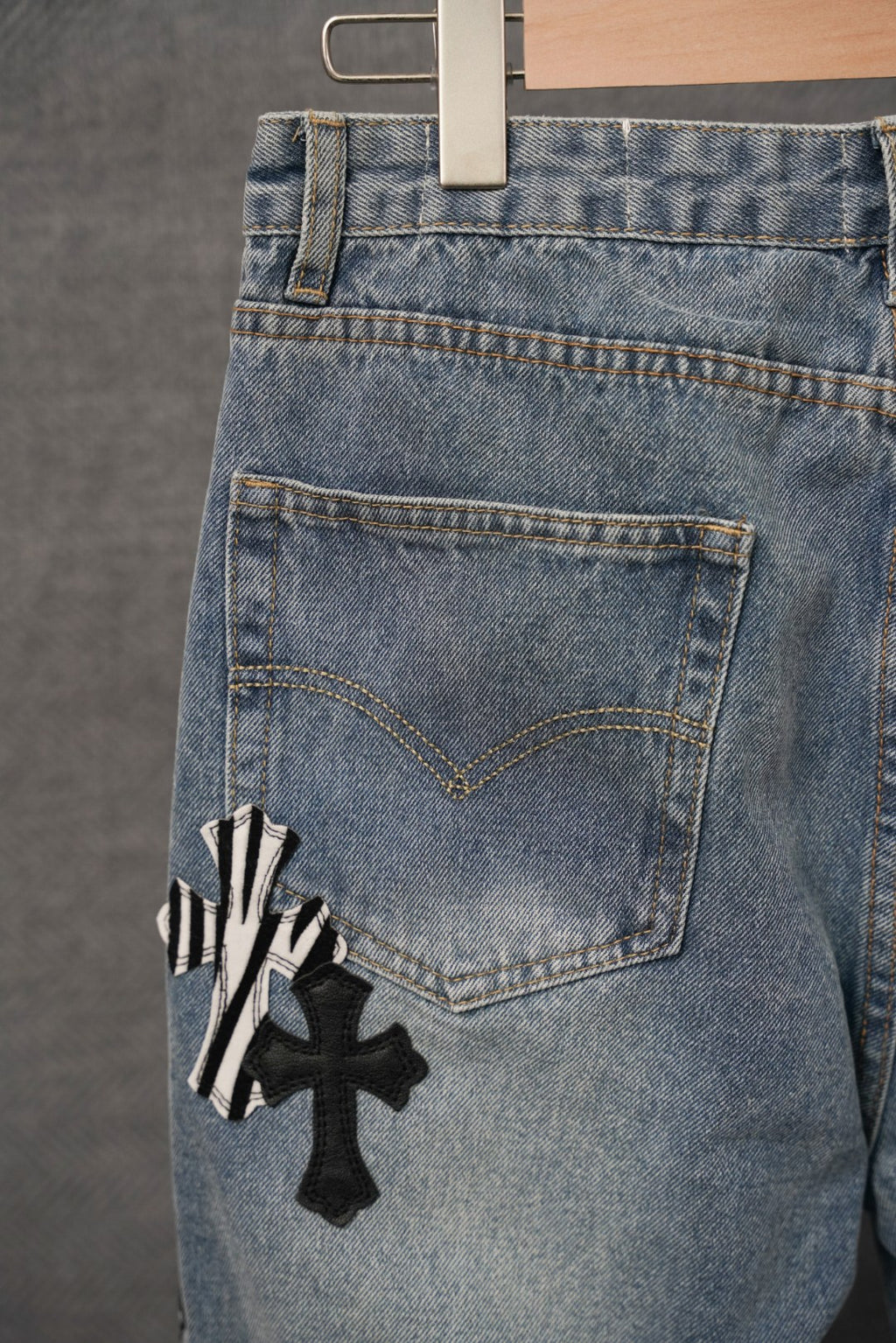 Light-wash denim jeans with rear pocket and black cross appliqué decoration