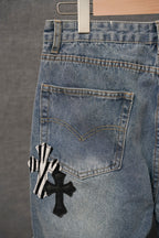 Light-wash denim jeans with rear pocket and black cross appliqué decoration