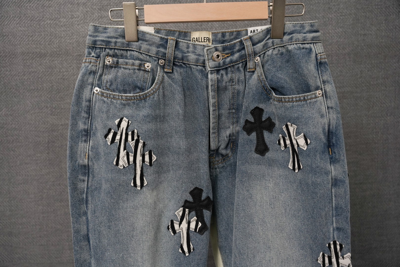 Light-wash denim jeans with back pockets and black cross appliqué pattern