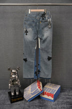 Light blue denim pants with black cross and striped patches; keychain tag detail