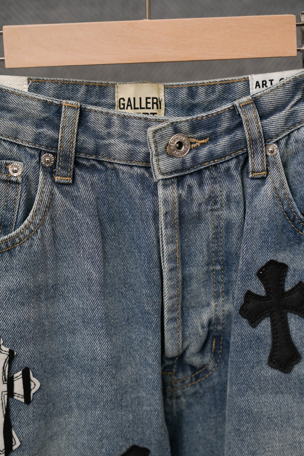 Light blue denim pants with dark cross graphics and stitched belt loops
