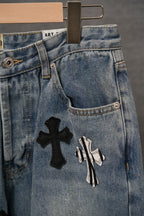Light blue denim pants with black cross and striped graphic patches on leg