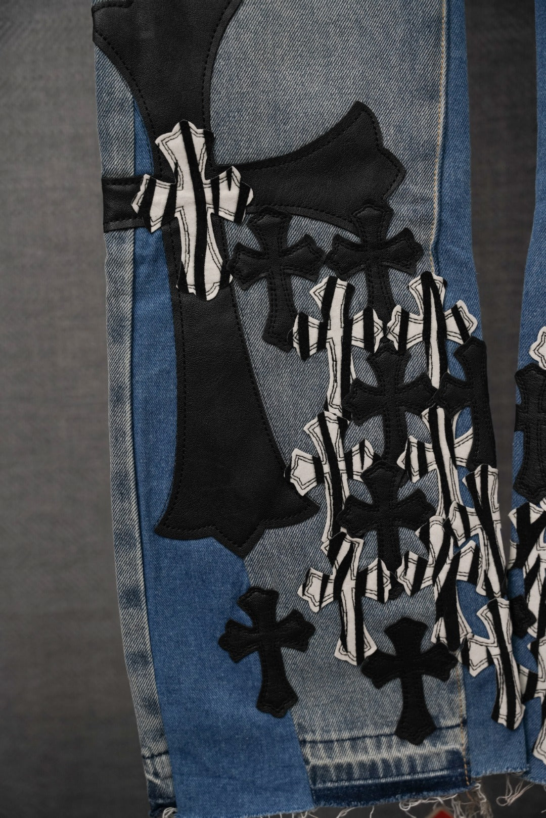 Light-wash denim jeans with layered black and white appliqué graphics on leg