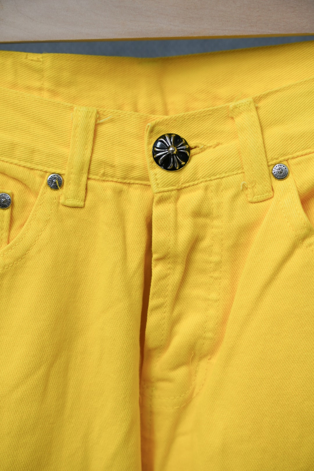 Chrome pants in bright yellow with front fly, belt loops, and metallic button accents.