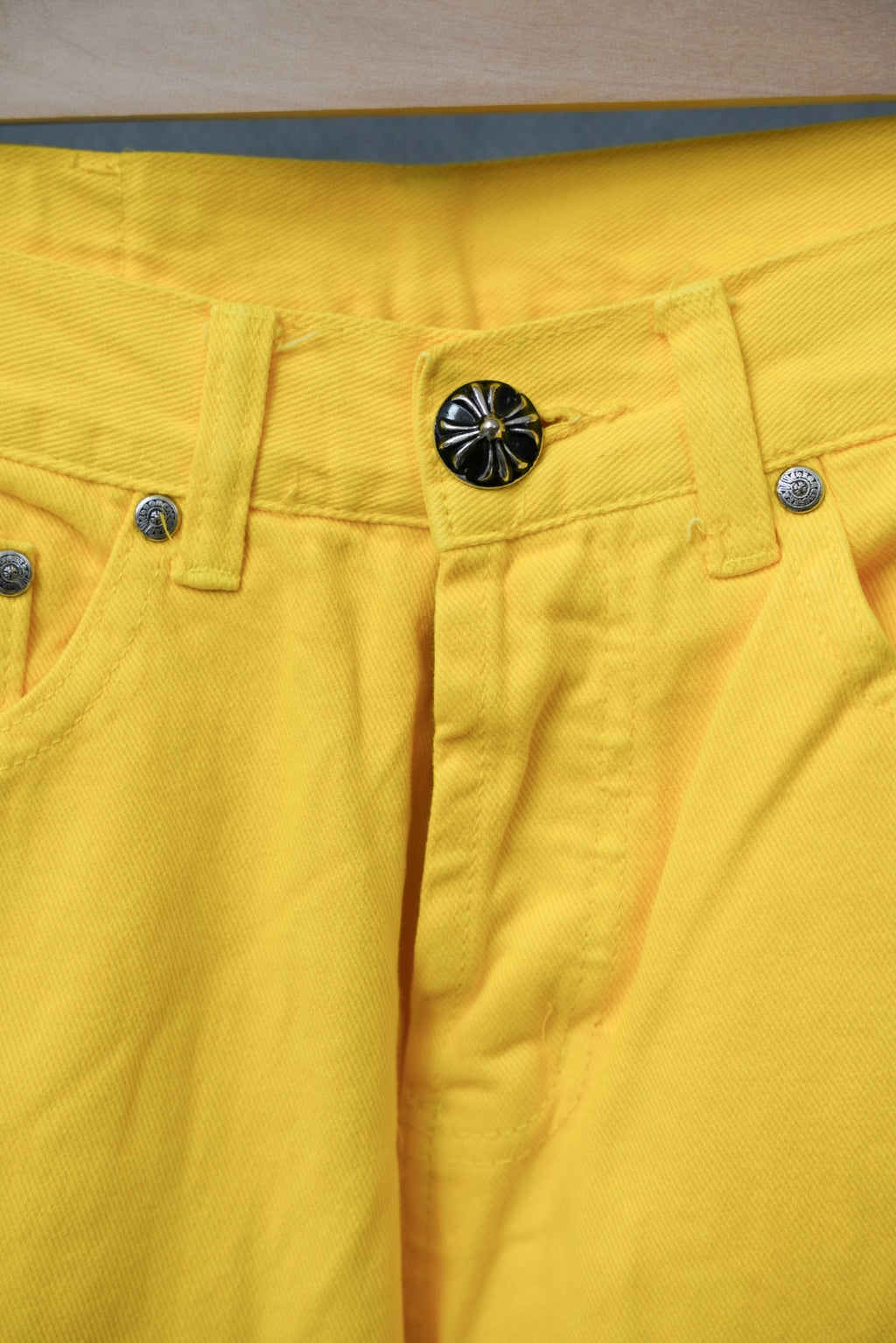 Yellow pants waistband with decorative button and zipper fly