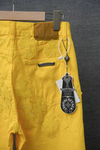 Yellow pants with embossed star pattern, logo patch, and hanging brand tag