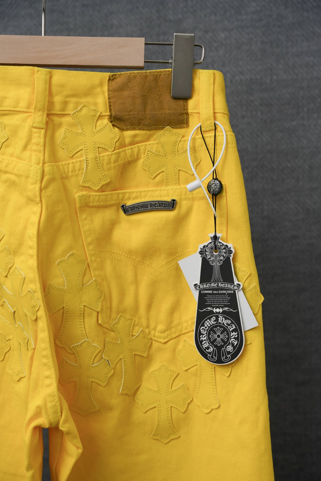 Yellow pants with embossed star pattern, logo patch, and hanging brand tag
