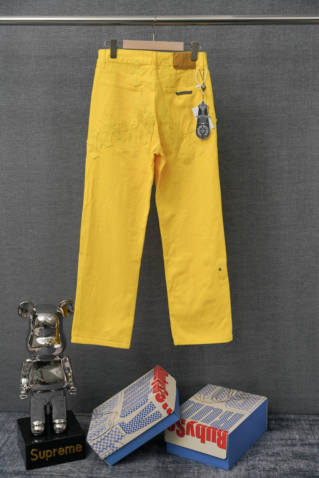 Chrome pants in bright yellow with belt loops and a hanging accessory at the waistband.