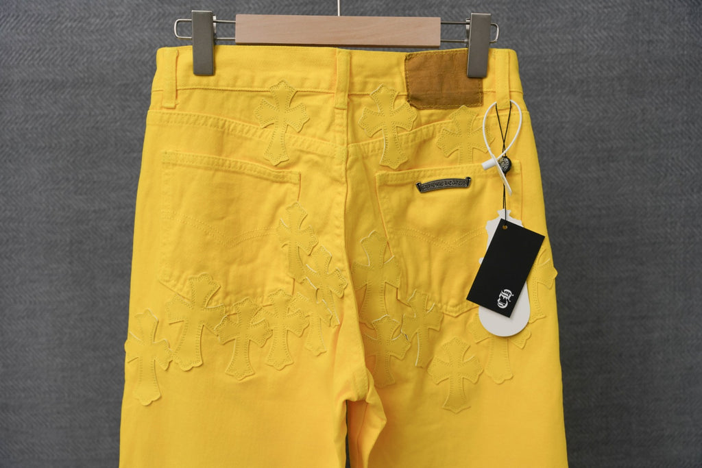 Chrome pants in bright yellow with patterned textural stitching and a hanging tag at the waistband.