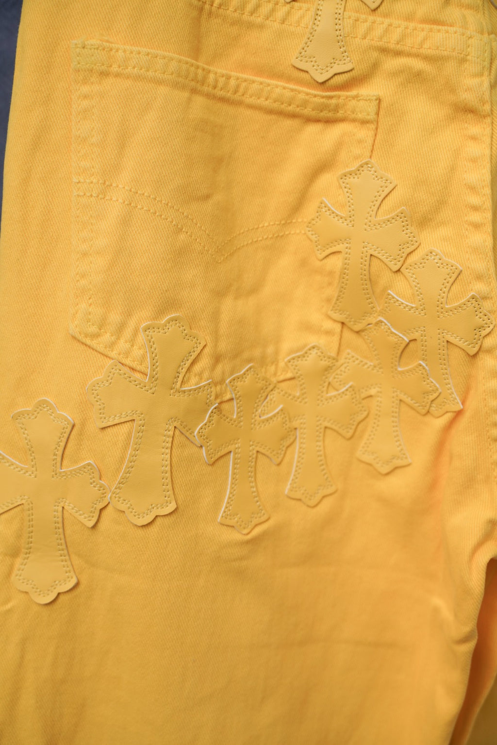 Chrome pants detail: yellow fabric with repeating cross-like embroidery