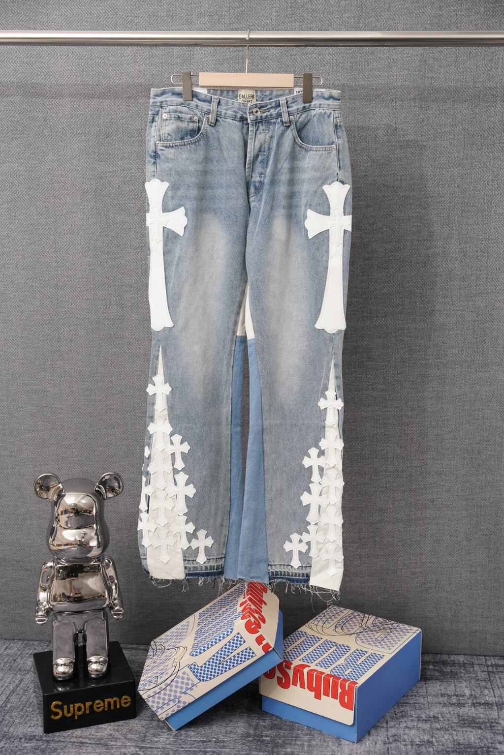 Light-wash denim pants with white cross appliques along both legs