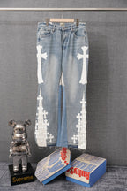 Light-wash denim pants with white cross appliques along both legs